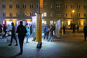 Auf dem Bild sieht man Menschen auf dem Campus für Demokratie, die sich die Open-Air-Ausstellung anschauen.