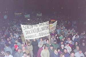 Auf dem farbigen Foto ist eine große Menschenmenge zu sehen, die mehrere Transparente über ihre Köpfe hält.
